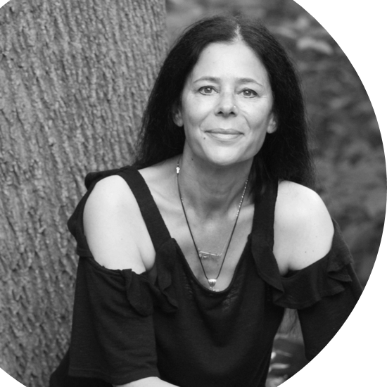 A black and white photo of a woman sitting in front of a tree.